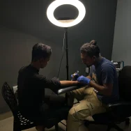 Top-Tattoo-Consultation-in-Kerala A skilled tattoo artist tattooing a client during a professional session-top tattoo consulation in kerala